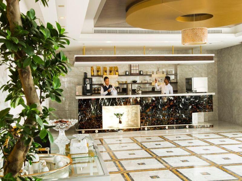 잔나 버즈 알 사라브 호텔 아부다비 외부 사진 The photo depicts a modern reception area or lobby, featuring a stylish check-in counter made of dark marble with a gold accent. Behind the counter, two staff members are engaged in work, likely attending to guests. The area is well-lit and has conte